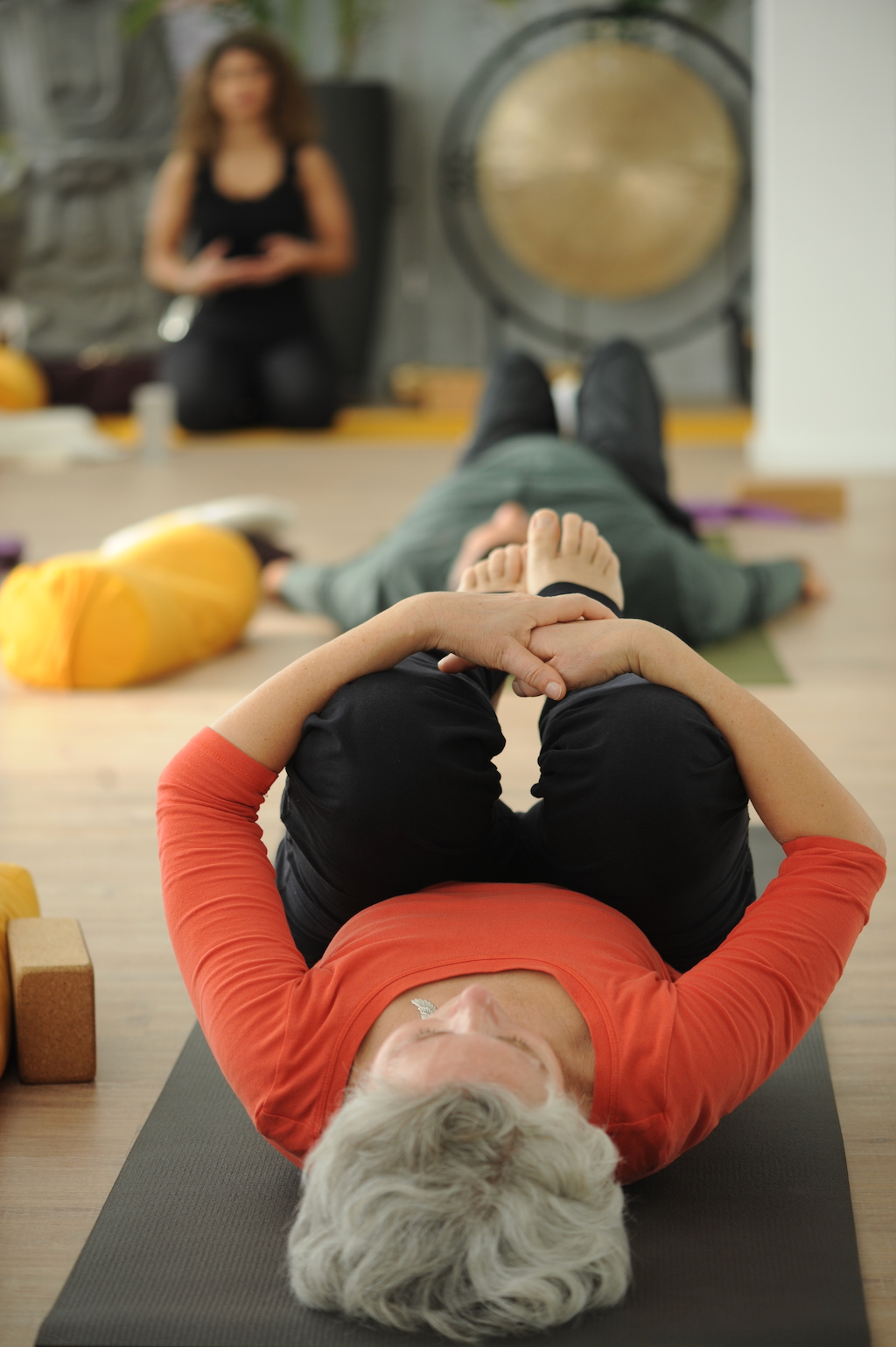 retreats Teilnehmerin liegt mit angezogenen Beinen auf dem Rücken auf ihrer Yogamatte