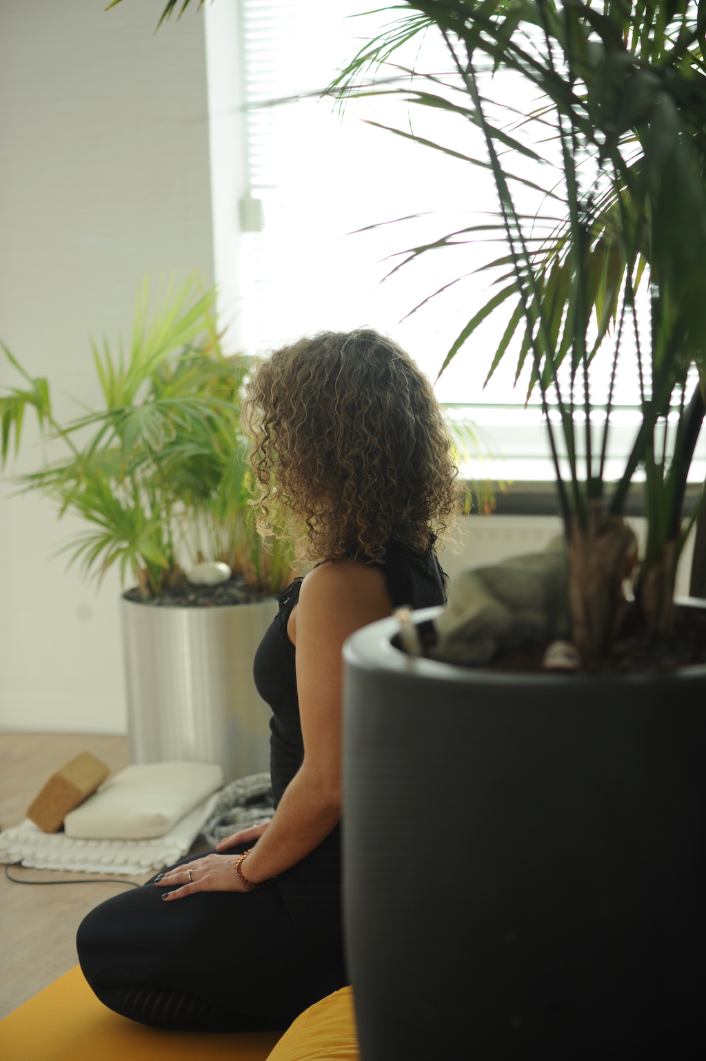 weinyoga Julia Robinson sitzt im Yogasitz auf ihrer Yogamatte im Kursraum